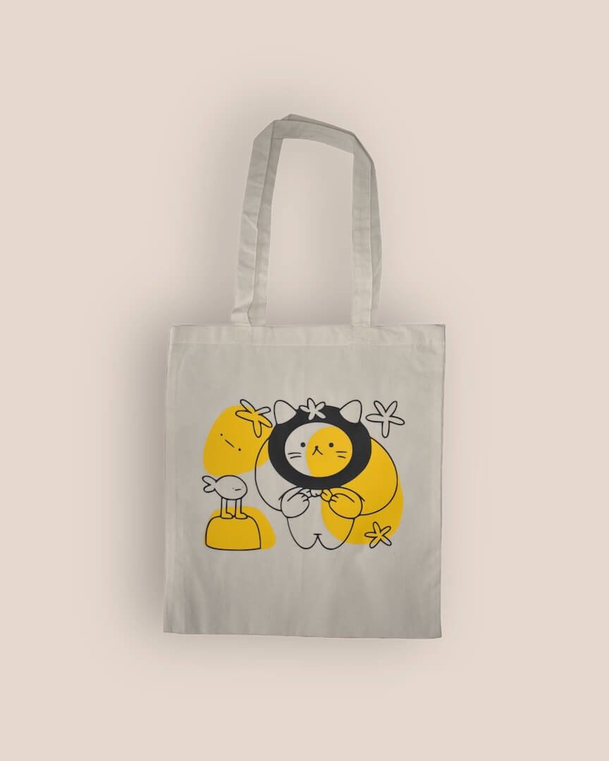 Vooraanzicht van de naturelkleurige ’Cat Adventure Tote Bag’ met een cat en zijn visvriend ontwerp in zwart en geel